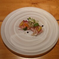 ラトリエ まる耕 - ▶前菜
                    ○南知多の天然鰤（ブリ）のマリネ
                    自家製のトマトのピクルス、バルサミコ酢が
                    添えてあるとの説明。
                    
                    天然ブリは見た目、食感、味わい共に
                    鮮度が良いのが一目瞭然❕