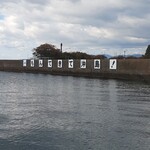 汀の精 - 定期船から沖島港を見て。「もんてきて(戻って来て)沖島！」の文字。
