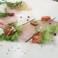 Serafina NEW YORK さいたま新都心店 - 葡萄と旬魚カンパチのカルパッチョ "Greater amberjack Carpacctio with grape with white balsamic"「ホワイトバルサミコの甘酸っぱいドレッシングで脂の乗ったカンパチと旬の葡萄。彩り豊かな野菜を飾り付けた一品。程良い甘味と酸味で仕上げたホワイトバルサミコのドレッシングで」