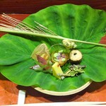 草喰 なかひがし - 八寸：ずいきの葉に透かしほおずき 卵黄の味噌漬を挟んだ銀杏、玉蜀黍の寒天、酢飯を詰めた茗荷の酢漬け、無花果と枝豆のきな粉酢和え、ごり、味女、ウドの花、のし梅を挟んだ里芋、キハダ、鮎のテリーヌを包んだ花オクラ、すすき