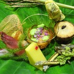 草喰 なかひがし - 八寸：透かしほおずき 卵黄の味噌漬を挟んだ銀杏、玉蜀黍の寒天、酢飯を詰めた茗荷の酢漬け、無花果と枝豆のきな粉酢和え、ごり、味女、ウドの花、のし梅を挟んだ里芋、キハダ、鮎のテリーヌを包んだ花オクラ