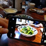 丸千葉 - レン草と牡蠣のバター炒め、を撮る彼女。