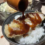 とんかつ憲進 - 常陸の輝きのリブロースかつをライスにのせてソースをかける
