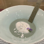 トゥ・ラ・ジョア イズム - 蓬の新芽　冷製スープ 白いのは自家製ベーコンの泡 ヨモギのチューイー（クッキー） 底には親指サイズの手作り大福 食用プラチナ  混ぜずに食べると箇所により味、触感、香りが変わって楽しめます 最後はお口の中で大福とヨモギでヨモギ餅になります