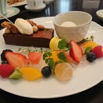 東京ステーションホテル ロビーラウンジ - ガトーショコラは生チョコみたいにしっとり濃厚｡生クリームとナッツがアクセント｡
      隣の器はレモンジェラート｡ デコレーションは柑橘のさっぱりジュレとフルーツ｡ レモンのマカロンとゼリーも。