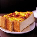 丸福珈琲店 - チーズトースト：
プロセスチーズを削って裏ごしし、卵黄や調味料を合わせて練り上げて独自の≪ネタ≫を作ります。
厚みのあるトーストが≪ネタ≫の持つコクのおかげで独自の甘みをもった味わいに変わる丸福自慢の一品です。