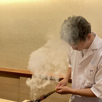 鎌倉 北じま - クエの皮めに炭を当てる北嶋氏
      室内に立ち昇る煙にも香ばしさが感じられます。
      炙った直後のクエをいただける、理に適った素敵な演出です♪