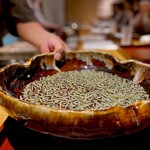 馳走 啐啄一十  - 僕くらいの年代から50歳くらいまでの方なら1度はテレビで見たことがあるんでは？ リーゼントに着物にたすき掛けした料理家、平野寿将。 そう、彼が広島で開いた店が本日お邪魔した「馳走 卒啄 一十」。 広島では堂々、No.1の評価。 今もあの頃と寸分たがわない姿で厨房にお立ちです。 僕と同い歳の1960年生まれ。 その大将ご本人が手にする蓴菜。 山の麓のきれいな水で育てられてるんだとか。