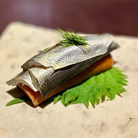 アカ - ❷小肌のボカディージョ ～スペシャリテである美しい小肌に魅入られた逸品。トマトを練り込んで焼きあげマリネしたトマトパンと小肌を大葉を包んで。握りのような酸味ある小肌とトマトパンが絶妙なマッチング。