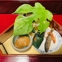 うかい鳥山 - カジの葉っぱで覆われた八寸。葉の上に光っている金箔が朝露を表しています。茄子の胡麻みそと瑞木の和物が素晴らしいおいしさでした。