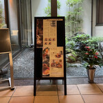INODA COFFEE - 店内の待ち合いの椅子の目の前には、中庭があり、メニュー表が立ててある。