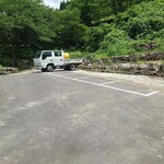 郷土料理 栃洞屋 - 駐車場
      道路沿いにお店の看板があり、
      看板近く（右側）の坂の上に駐車場がある
      （車高の低い車だと厳しいと思われる）