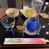 Soba CAFE 輝 - 日本酒・一本木。ちょっとした突出し付き。ここからだと見えにくいが瓶子の中央部に氷が入れられるようになってて冷で飲める。