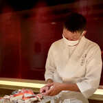 千葉たかおか - 高岡さんが太刀魚棒寿司に炭火を当てている所
                                何気にやられてますが、炭火はかなり高温で熱いのだと思います。
                                チリチリと脂が焼ける香りがカウンター越しに、早く食べたい、皆さんそう思っていますよ間違いなく。