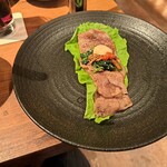 焼肉うしごろ - ハサミで半分に切り、ポン酢に浸けた大判サーロインをサンチュの上に敷き、ナムルやニンニク焼きなどをのせたもの・その1です。