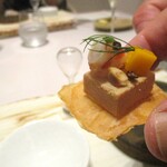 レミニセンス - フォアグラ：フォアグラのテリーヌの下には板状にしたジャガイモのフリット、上には車海老、マンゴー、ナッツ etc．にフェンネルが飾られています。こちらも手に取っていただきます。 70秒分の白い砂が入った砂時計と共に お料理は提供されます。フォアグラの濃厚な味わいを砂時計の砂が落ちきるまで楽しみます。  そして・・・、余韻を残しつつ 次のお料理をいただきます。