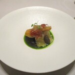 レミニセンス - サスエ：静岡県焼津に在る 日本一美味しく魚を仕立てると多くの料理人たちから評価の高いサスエ前田から仕入れた金目鯛が 鱗を付けた状態で 脂ののりがよくフンワリと仕上げられています。上には超薄切り神戸牛の生ハム、下には冬瓜のすり流しが敷かれ、キノコとムカゴが添えられており、深いグリーンが美しいシブレットのソースでいただきます。