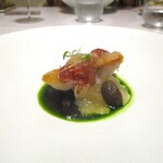 レミニセンス - サスエ：静岡県焼津に在る 日本一美味しく魚を仕立てると多くの料理人たちから評価の高いサスエ前田から仕入れた金目鯛が 鱗を付けた状態で 脂ののりがよくフンワリと仕上げられています。上には超薄切り神戸牛の生ハム、下には冬瓜のすり流しが敷かれ、キノコとムカゴが添えられており、深いグリーンが美しいシブレットのソースでいただきます。