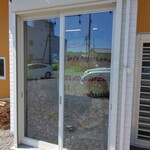 La Magica - 駐車場側から見えるピザ釜と大量の薪の束　　　反射で私の車が映っていますが、拡大して見ると中に釜と薪があります。