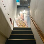 田中圭英 - 2階に上がる階段の先には田中シェフのパネルが！