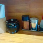 ラーメン 盛太郎 - カウンターにある諸々。黒い壺には「お残し厳禁」な刻み玉ねぎが入っとります。辛い理由がわからない玉ねぎは大好きなので沢山投入しますが、スープは残すも玉ねぎは綺麗にさらいます。