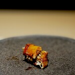 くるますし - アナゴ。 笹の葉から取り出されたのは、これも蒸し工程なしの、食感をしっかり残したアナゴ。 江戸前のふわふわとろとろのアナゴも美味しいですが、こうしたアナゴもありのあり。 熱々のアナゴに温かいシャリ。 タネによってシャリの温度を変えるのは、鮨屋では完全にスタンダードになりました。 これ、仕事量をかなり増やしてしまうんですどね。