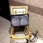 コトカフェ - 明治通り沿い、花園神社の鳥居の近くにあります。この看板を目印に。