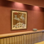 緒方 - 暖簾を潜って待ち合いとなっている「店の間」、土壁の綺麗な「通り庭」を通って板場とカウンター8席のお部屋へ
      秋らしい紅葉と鹿の裃の絵が掛かっています
