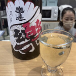 酒や おおたけ - 2杯目は(前回お勧めされた酒と同じ銘柄の)『樂の世』。昔あった愛知の米「ゆめまつり」を復活させそれを酒米にした日本酒とのこと。酸味と甘味のバランスがよい。(なにげに多めに注がれている？)