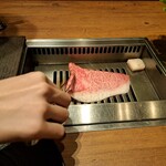 焼肉うしごろ - 牛脂を塗った網の鉄板で、北海道産黒毛和牛A5サーロインを焼く様子その1です。
