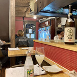 焼鳥クロカル - 店内風景(自視点)。ワイングラスの横にあるのはチェイサー用のミネラルウォーター。席料300円はこの代金と思えばいいかと。