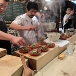 食堂 おがわ - “根付き芹とお揚げの炊いたん”。の盛り付け風景。ちゃちゃっと…。手際抜群、料理の味を確実に引き立ててます。