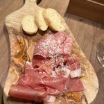 ビストロ巴里食堂 - 削りたて生ハムとサラミの盛り合わせ。撮影前に一切れ食べてしまった。フレッシュでパルミジャーノがかかっているので、そのままバゲットと合わせて食べられます。