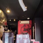 Karashibi Miso Ramen Kishin - 店内は黒塗り壁と仁王像の描かれた赤い壁、オープンキッチン、衝立の高いカウンターが詰まったコンパクトな間取りです
                        お席はL字カウンター7席、運営は店長さんのワンオペ