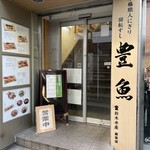 回転寿司 豊魚 - ビル1階のさかな屋さんの脇にある入口。
            お店はこのドアを入って階段を2階に上がったところ。