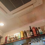 アジアンダイニング ダリマ - レジカウンターの頭上の棚には各種アルコールの瓶がずらり