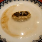 京極寿司 - ▷アワビの姿煮
      このお店の定番料理となる
      アワビを水と塩と酒だけで柔らかくなるまで煮詰めていって、アワビから出たお出しを葛で溶いて餡にしている
      上に乗っているのは酒蒸ししたアワビの肝となる