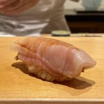 鮨 はしもと - 鰤 氷見
      コロンとした赤酢のシャリを、大きく切付けた鮨種でくるりと包み込む様なフォルムが特徴。
      それも種によりシャリの大きさにも若干の変化を持たせています。
      強い鰤の脂も実に落ち着きのある味わいです。