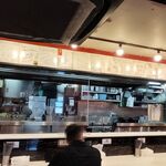 蒙古タンメン中本 - 厨房の様子と、カウンター上の沢山のサイン