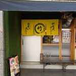竹岡式ラーメン まる竹 - 黄色い暖簾が目立つ店舗入口。黄色地に緑の文字は、黄色いカレーと竹の色を表しているのだろう。
