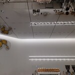 アラビカ東京 麻布台ヒルズB1店 - 眩いばかりの白を基調とした店舗。金色のカップと地図が映える。コーヒーの世界では中南米〜アフリカを中心とした世界地図が主流だ。