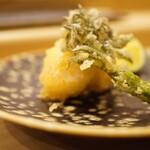 鮨 大門 - 薄い衣を破るとクリーミーに溢れ出す白子。雑味のない香りは吐息までもおいしさであふれ、一摘みのお塩で輪郭をつくる。 そしてタラの芽からも一口でふわっと鼻から抜けていく春の香りを添えて。