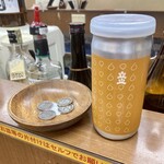 佐野屋 - 日本酒(立山、300円)。1組1つずつ割り当てられる「木皿」は、お釣り入れと支払い用の“デポジット”の役目をしている(お釣りはしまわない)。お札以外はここを経由してキャッシュオンを実現している。