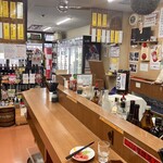 Sanoya - 店内風景。かなりしっかりしたカウンターが店舗の奥側にある。この写真の奥手が入り口側で販売エリアとなっていて、角打ちエリアに1番近い場所にある冷蔵庫に呑める酒類が置いてある。