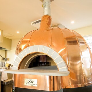 大きな専用窯で焼き上げる自家製ピザや窯焼き料理