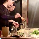 Okonomiyaki Imari - 焼き手が休みなく焼き続けています。鉄板と木製カウンターが一体なので、ライブ感満載