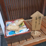 丸屋 - 待ち用縁台には自由に持ち帰れる揚げ玉。普段は中に入ってすぐ左の台の上にあります。