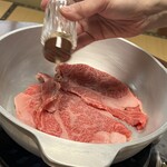 牛銀本店 - ガスに火をつけて鍋が温まる前に牛肉を投入し胡椒を振りかけます