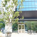 タリーズコーヒー - ビル街の緑に位置する店舗のファサード。