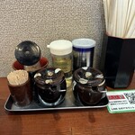 横浜家系らーめん 天王家 - 卓上調味料。ツボの中は緑色のニンニク（行者ニンニクかな？）と豆板醤（こちらは入れませんでしたが、赤みがかっていたのでおそらく）です。